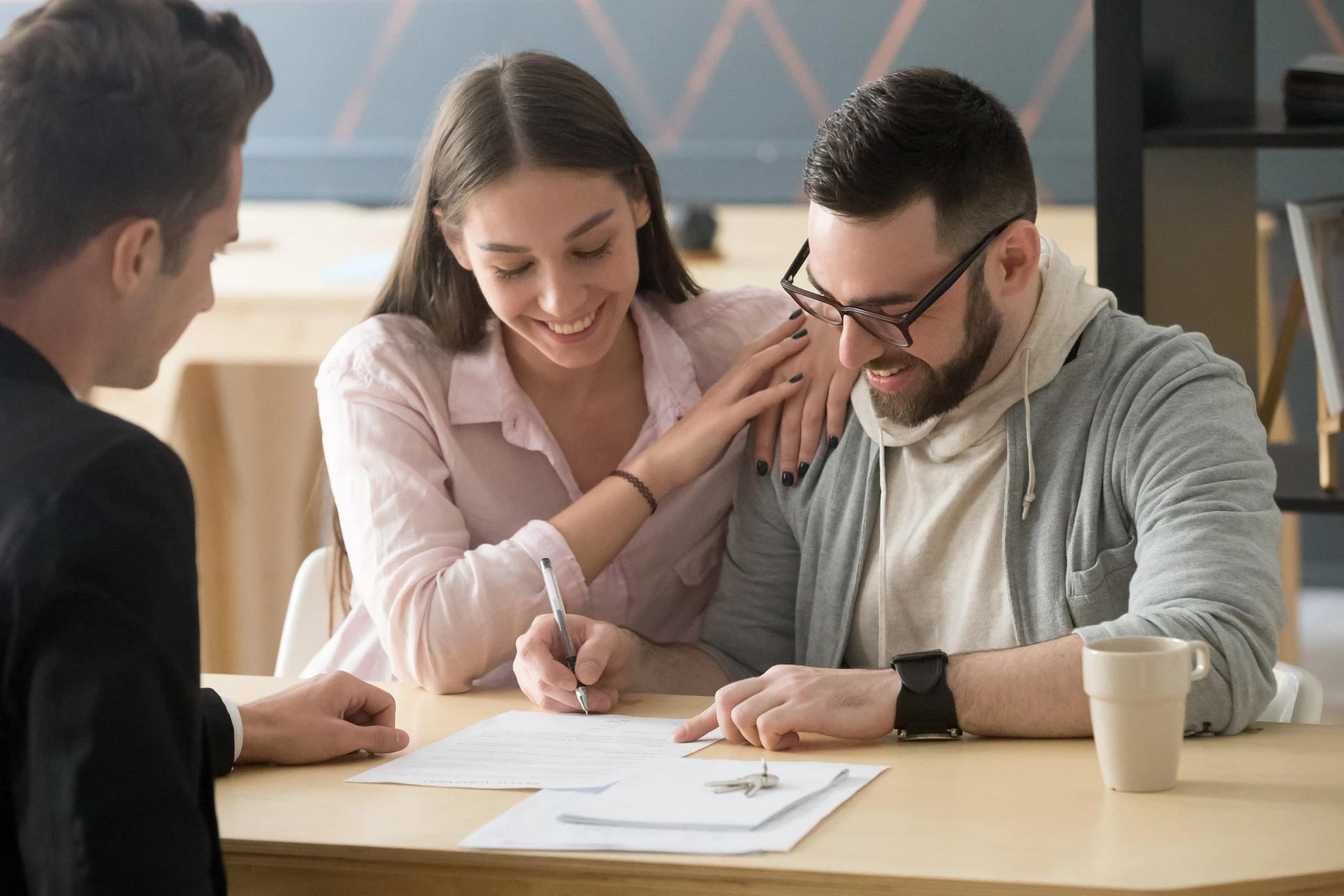 Scène intérieure de bureau moderne avec un couple signant des documents face à un professionnel